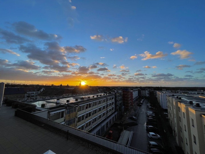 Das Bild zeigt einen Sonnenaufgang über den Dächern von Bernau bei Berlin.