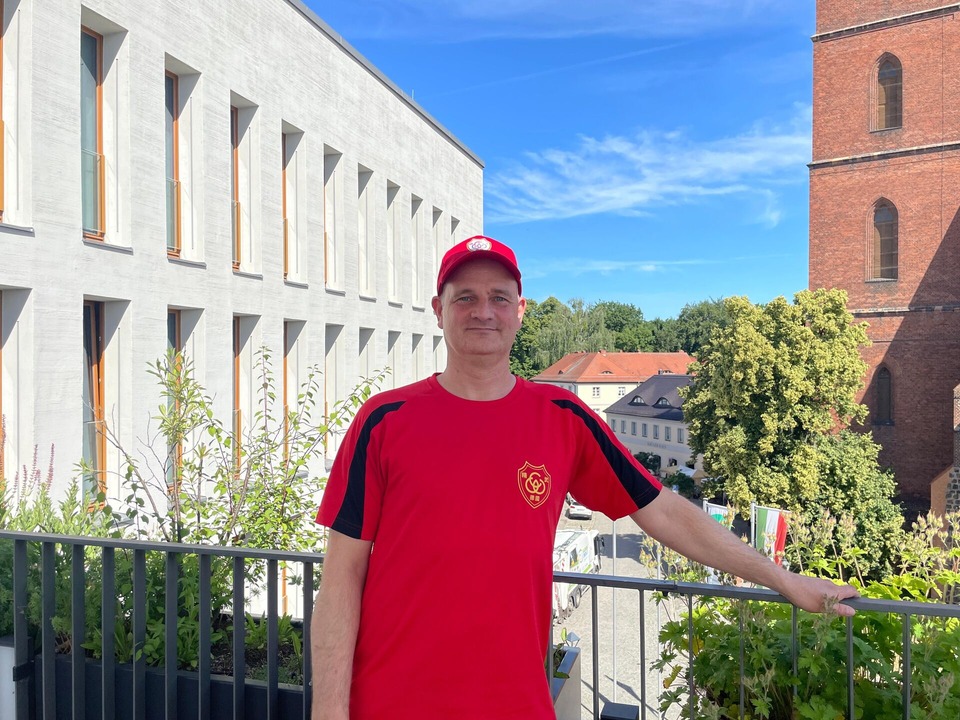 Mann mit Roten T-Shirt und Roten Cap steht auf der Dachterrasse des Neuen Rathauses in Bernau