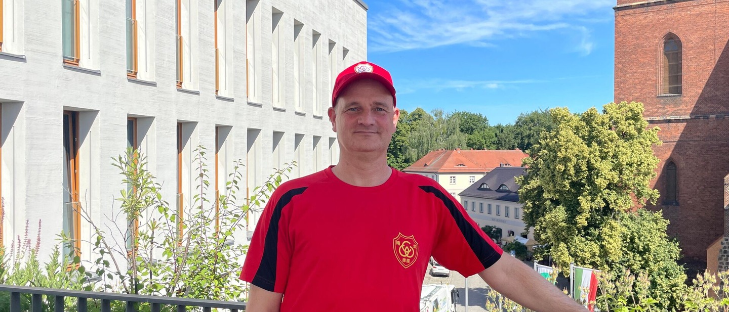 Mann mit Roten T-Shirt und Roten Cap steht auf der Dachterrasse des Neuen Rathauses in Bernau