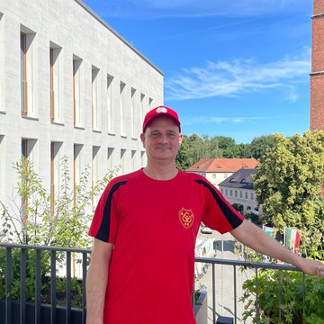 Mann mit Roten T-Shirt und Roten Cap steht auf der Dachterrasse des Neuen Rathauses in Bernau