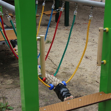 Eine Nahaufnahme eines neuen Spielgeräts mit bunten Kordeln, die eine Hängebrücke tragen. 