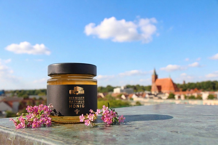 Ein Glas Rathaushonig, im Hintergrund die Skyline der der Stadt Bernau.