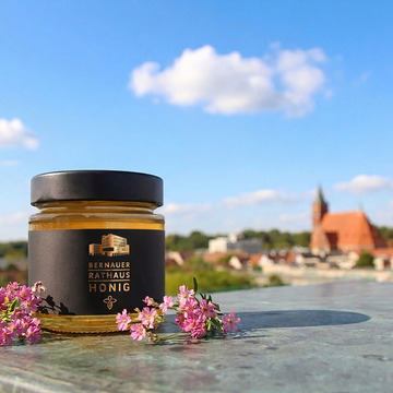 Ein Glas Rathaushonig, im Hintergrund die Skyline der der Stadt Bernau.