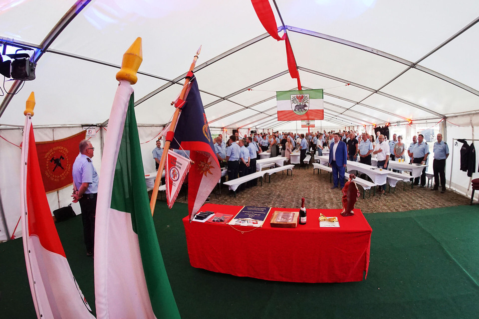 Festzelt mit Zahlreichen Feuerwehrkameradinnen und -kameraden. Die Flagge Bernaus hängt an der Zeltdecke. 