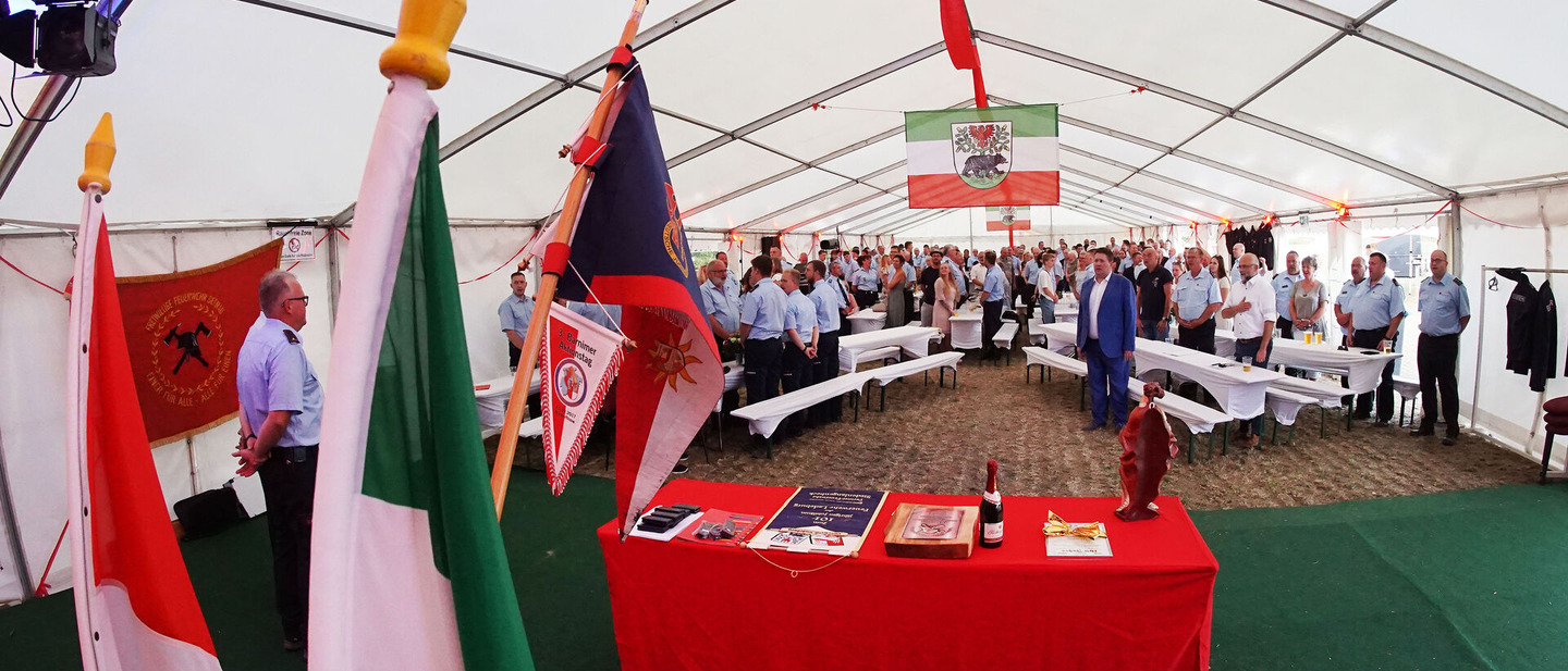Festzelt mit Zahlreichen Feuerwehrkameradinnen und -kameraden. Die Flagge Bernaus hängt an der Zeltdecke. 