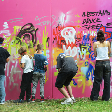 Kinder und Jugendliche probieren sich an der Graffitiwand aus.