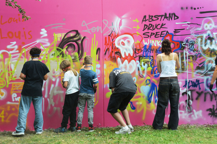 Kinder und Jugendliche probieren sich an der Graffitiwand aus.