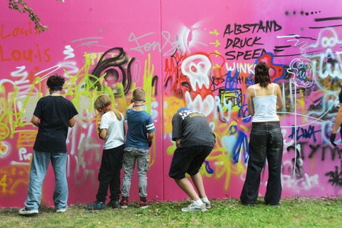 Kinder und Jugendliche probieren sich an der Graffitiwand aus.