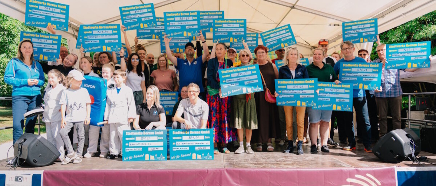 Man sieht auf dem Foto eine Gruppe Menschen, die von den Stadtwerken einen Spendenscheck bekommen haben