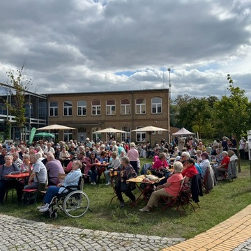 Viele ältere Menschen sitzen im Innenhofe der Kulturhofs. 