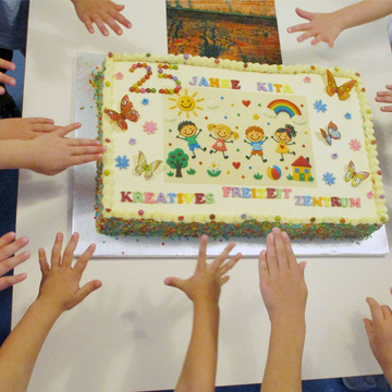 Das Bildzeigt Kinderhände, die zu einer Geburtstagstorte greifen