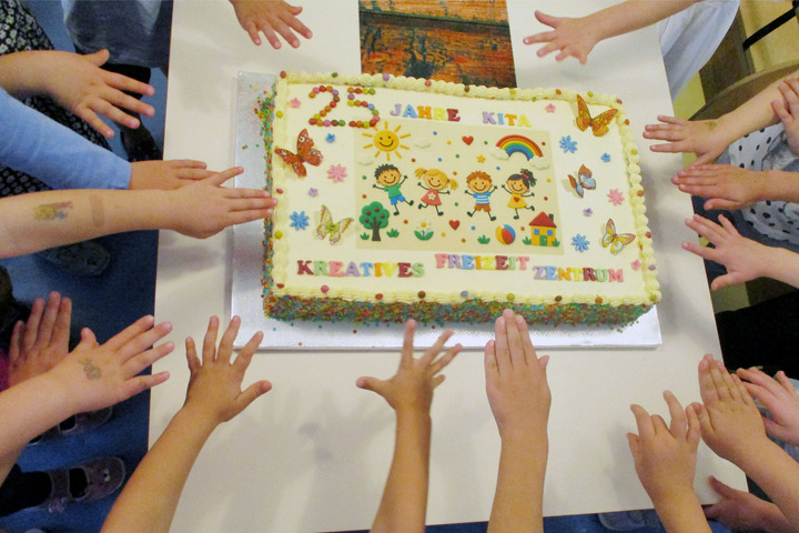 Das Bildzeigt Kinderhände, die zu einer Geburtstagstorte greifen