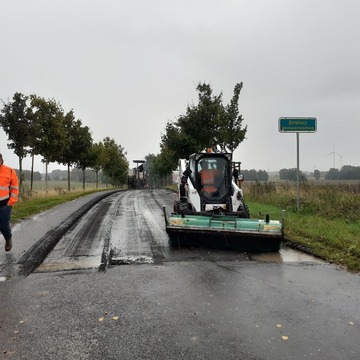 Eine Baumaschine verlegt neue Fahrbahn. 