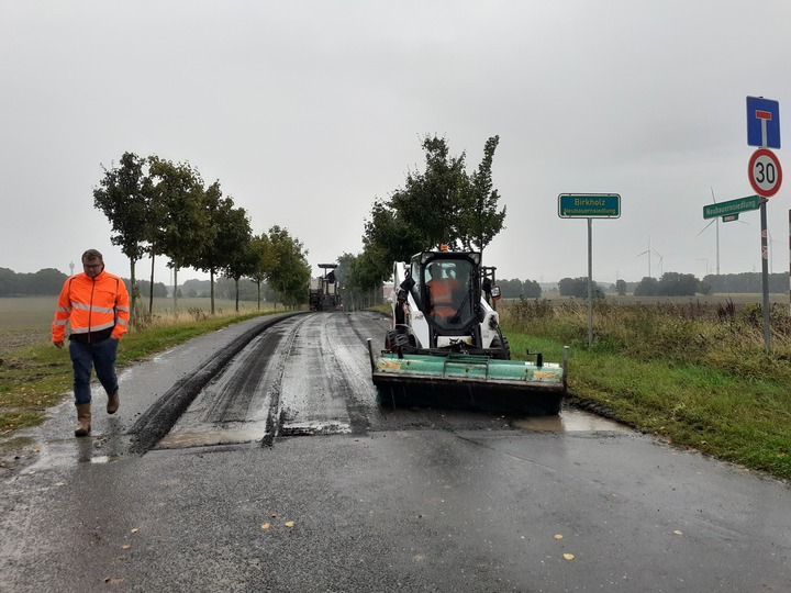 Eine Baumaschine verlegt neue Fahrbahn. 