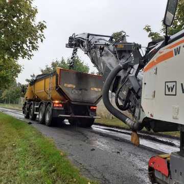 Zwei Straßenbaufahrzeuge stehen auf einer Straße.