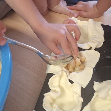 Kleine Backförmchen werden mit Äpfeln gefüllt.