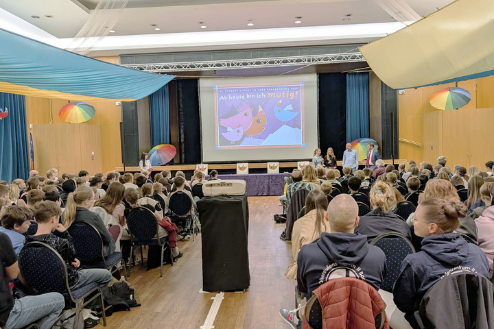 Ein voller Saal, die jungen Gäste blicken auf die Leinwand.