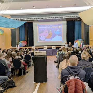 Ein voller Saal, die jungen Gäste blicken auf die Leinwand.