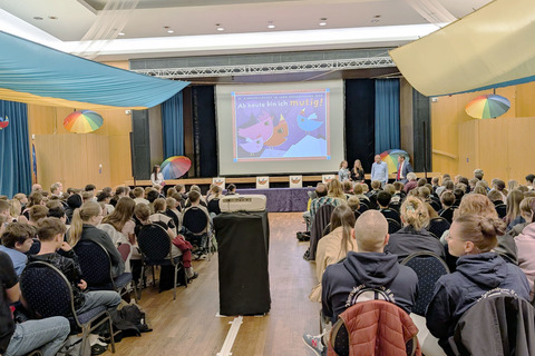 Ein voller Saal, die jungen Gäste blicken auf die Leinwand.