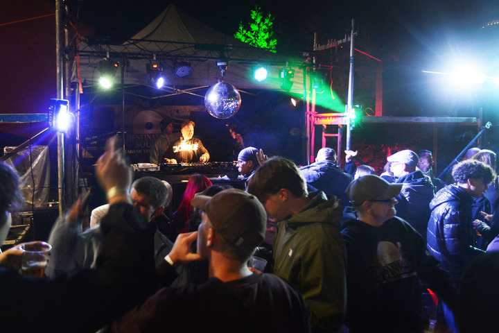 Das Bild zeigt eine Bühne mit DJ und Publikum von der vorherigen Lokaltour