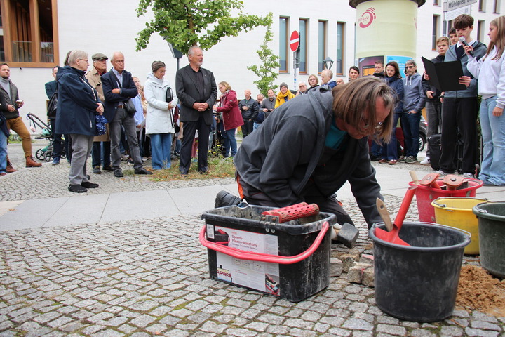Das Bild zeigt den Künstler Gunter Demnig bei der Verlegung der Stolpersteine