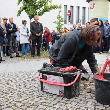 Das Bild zeigt den Künstler Gunter Demnig bei der Verlegung der Stolpersteine