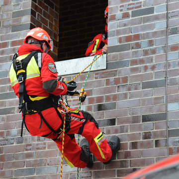 Ein Feuerwehrmann seilt sich von einem Haus ab. 