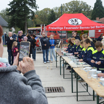 Die Kinderfeuerwehr präsentiert kleine Übungen an einer langen Tafel. Die Gäste fotografierten die Nachwuchstalente. 
